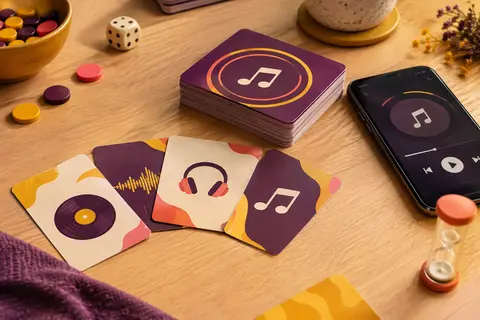 Cartes en papier cartonné d’un quiz musical disposées sur une table en bois clair, avec un smartphone à proximité.