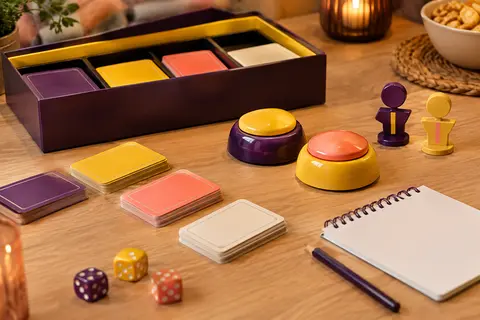 Cartes multicolores, deux buzzers et des totems d’équipe réunis sur une table de jeu