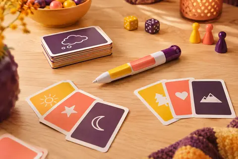 Stylo de dessin multicolore et cartes-indices posés sur une table de jeu en bois clair